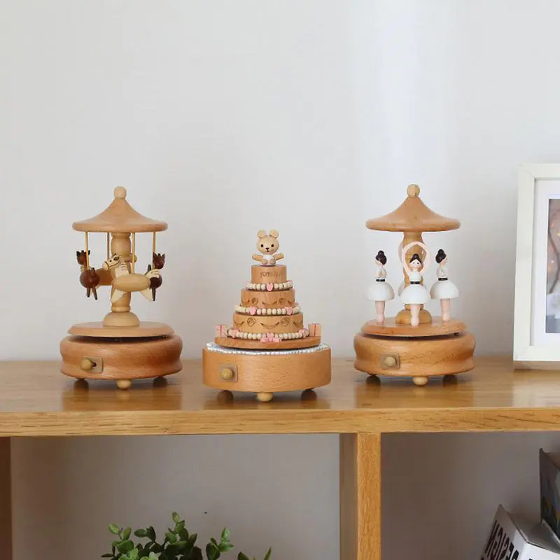 A shelf adorned with wooden figurines features delightful scenes: a bear atop a cake, a boy on a swing, and children in white garments circling a pole. Completing the nostalgic decor is the Valga Music Box - Vintage Wood, positioned beside a small plant on the left and an heirloom gift photo frame on the right.