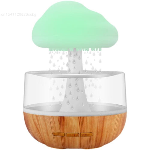 Introducing the Desktop Rain Cloud Humidifier by Valga, a tree-shaped humidifier with a wooden base that creates a soothing atmosphere. The top part is green, resembling a tree canopy, and appears to release mist depicted by water droplets. It features a clear middle section and three buttons on the front for control, doubling as an aromatherapy diffuser.