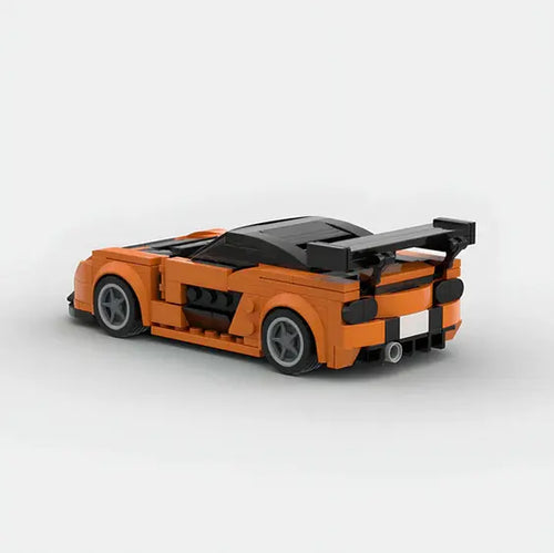 A Lego Car Mazda by Valga, styled as a sporty, orange two-door coupe with a black roof and large rear spoiler. The car features sleek detailing, gray rims, and iconic Mazda design elements, captured against a plain white background.