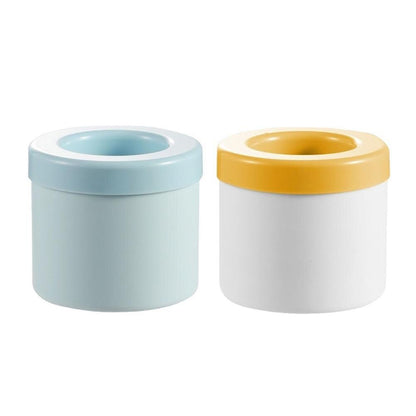 Two cylindrical containers are side by side. The left container resembles a Valga Silicone Cylinder Portable Ice Maker Bucket in light blue with a matching lid, while the right container is white with a yellow lid. Both have wide openings and minimalist designs.