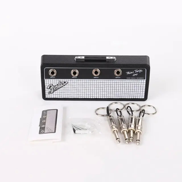 The Valga Wall Mounting Guitar Amp Key Hanger is a miniature guitar amplifier key holder featuring four input jacks at the front. This rockstar-themed accessory includes guitar plug keychains and comes with mounting screws, wall plugs, and an instruction manual for easy installation.