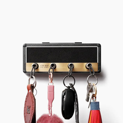 The Valga Wall Mounting Guitar Amp Key Hanger is designed to resemble a guitar amplifier. It features four input jacks used as hooks, each capable of holding various items such as guitar plug keychains, car keys, and keys with red tassels. The top of the holder showcases the text "JCM 800 Lead Series," adding a rockstar vibe to your space.