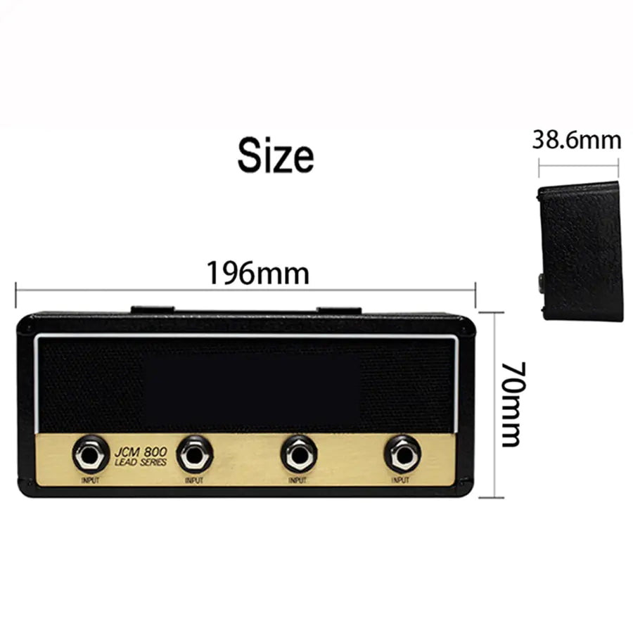 The Valga Wall Mounting Guitar Amp Key Hanger is shown in striking black and gold tones, with its dimensions labeled: width 196mm, height 70mm, and depth 38.6mm. The front panel features three hooks designed to look like input jacks labeled "INPUT," with the bold label "JCM 800 LEAD SERIES" beneath them, embodying a rockstar style.