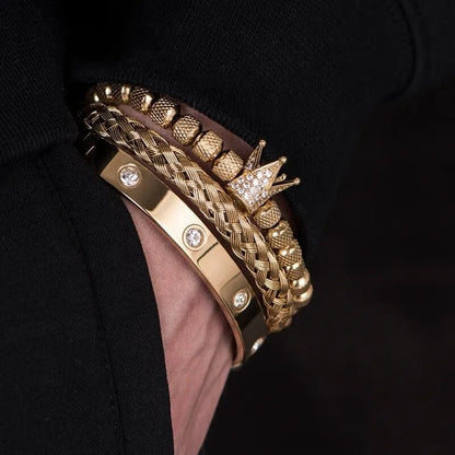 A close-up shot reveals a wrist elegantly adorned with four Valga Diamond Roman Bracelets. This exceptional design boasts a variety of textures, including a braided band, a beaded bracelet, one shimmering with small diamond-like stones, and another featuring a crown emblem encrusted with tiny crystals.