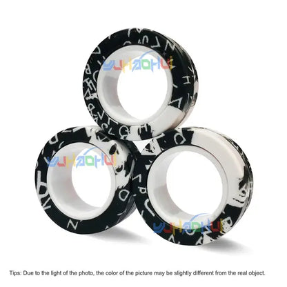 The Valga 3Pcs Magnetic Rings Anti-Stress are arranged in a triangular formation, similar to a fidget spinner. The rings are white with an outer black surface adorned with an assortment of white letters and symbols. A light reflection partially obscures part of the design, and there's a note below regarding potential color variation.