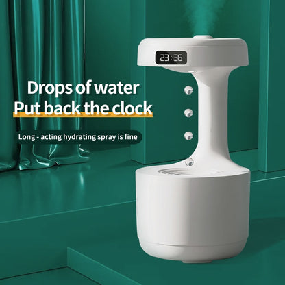 A modern Valga LED Water Drop Humidifier Diffuser, featuring whisper-quiet technology and a digital clock on top displaying the time 23:36, is placed against a teal curtain backdrop. The text on the image reads: "Drops of water put back the clock. Long-acting hydrating spray is fine.