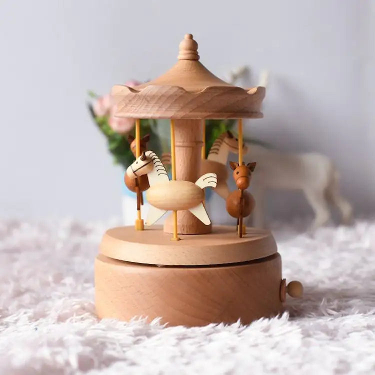 A Valga Music Box - Vintage Wood is elegantly displayed on a fluffy pink surface, evoking a sense of nostalgic decor. The music box features small, intricately carved animals such as a horse and giraffe. The background is softly blurred with floral elements and another decorative object visible, making it an ideal heirloom gift.