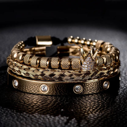 A close-up shot of Valga's Diamond Roman Bracelets showcases their exceptional design. One bracelet features a sophisticated braided pattern, another stands out with textured beads and a crown charm adorned with small diamonds, while the third is a solid band embedded with diamonds. These luxury bracelets by Valga are elegantly displayed on a dark surface.