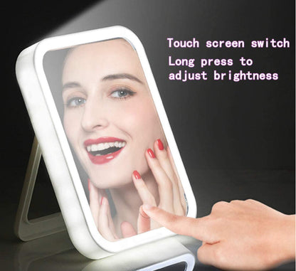 A person touches the screen of the Valga Smart Makeup Mirror, causing the LED lights around the edge to illuminate. Their reflection shows them smiling with red nail polish. The text on the image reads, "Touch screen switch, Long press to adjust brightness.