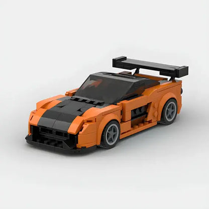 The Valga LEGO Car Mazda, a miniature model with an iconic orange body and black stripes, features a large black rear wing and meticulous detailing that perfectly replicates the design of a sports car. This excellently engineered model is displayed against a plain white background.