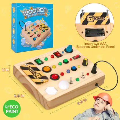 A Valga Montessori LED Busy Board for children is displayed, featuring an array of colorful buttons, switches, and lights. The board's dimensions are 6.9 inches by 5.9 inches by 1.1 inches. A child wearing an orange helmet is looking up at the interactive LED busy board, with the product box visible in the background.