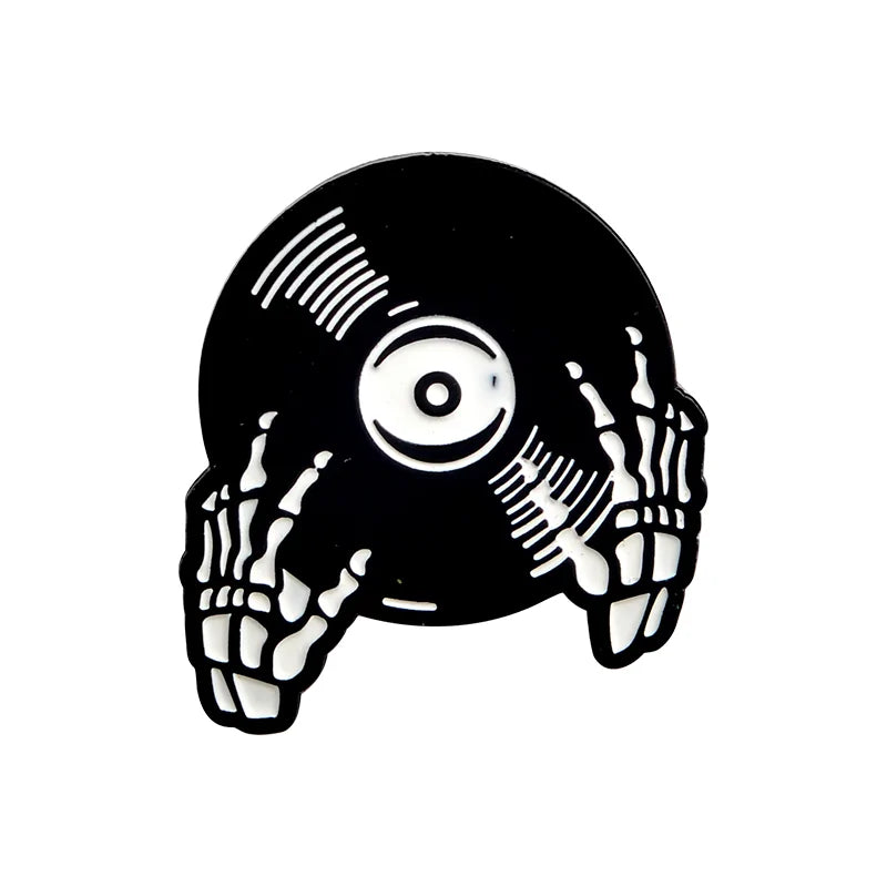 An illustration from Valga of a black vinyl record being held by two skeletal hands. The record, featuring white lines as grooves and a white label in the center, is gripped from opposite sides by the skeleton hands, creating a spooky, retro aesthetic perfect for the Punk Music Lovers Enamel Pin.