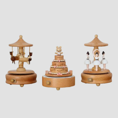 Three Valga Music Box - Vintage Wood pieces on display: the left one features a carousel with reindeer, the middle one showcases a tiered cake topped with a bear figure, and the right one shows two ballerinas dancing under a circular canopy. These charming pieces make perfect heirloom gifts and nostalgic decor for any home.